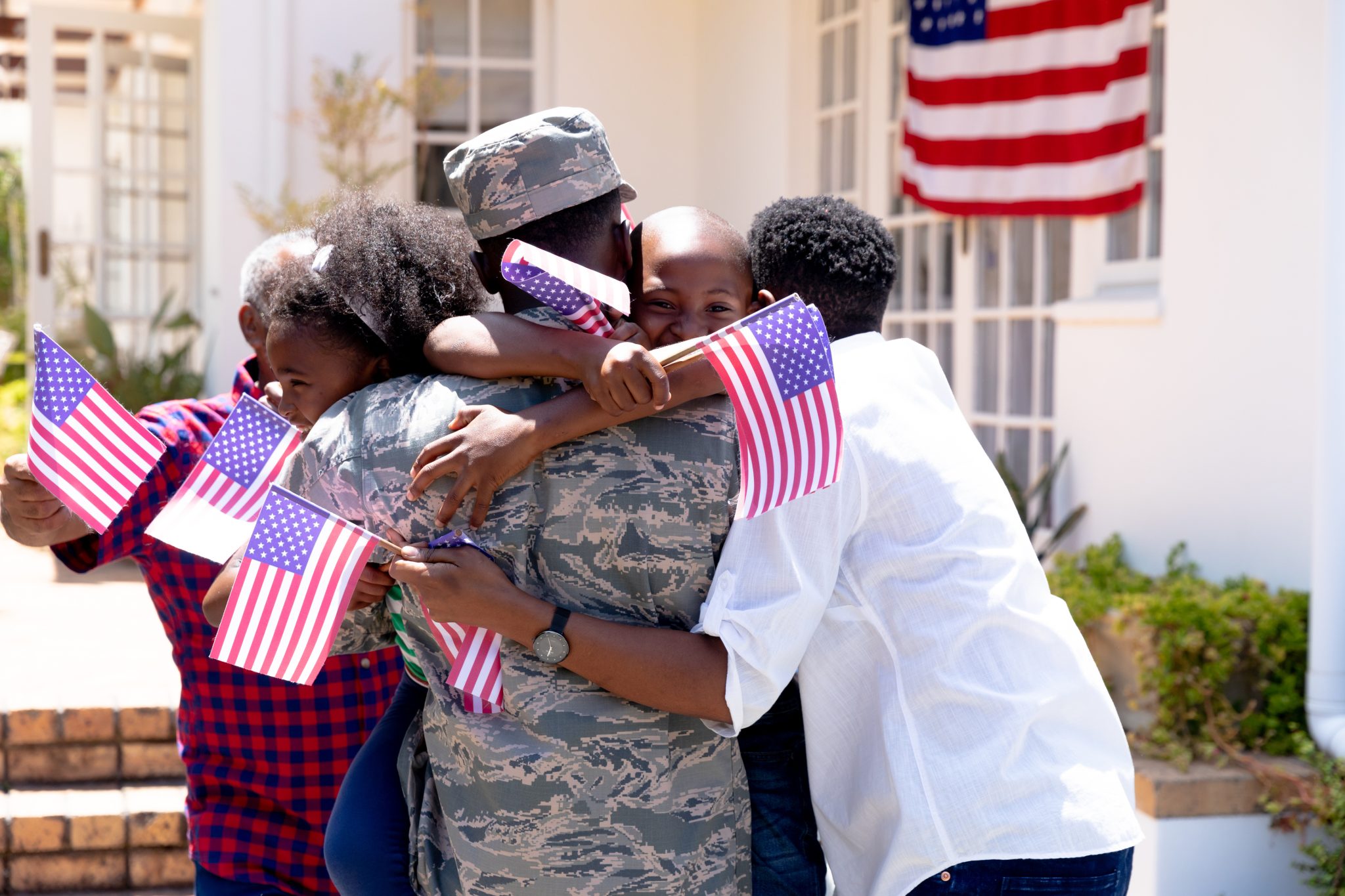 African American male soldier wearing uniform and his family standing by their house