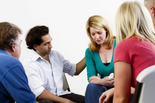 Support group comforting grieving woman