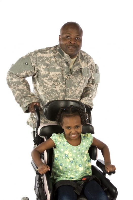 Military father pushing child in wheelchair