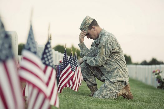 Soldier kneeling at military grave