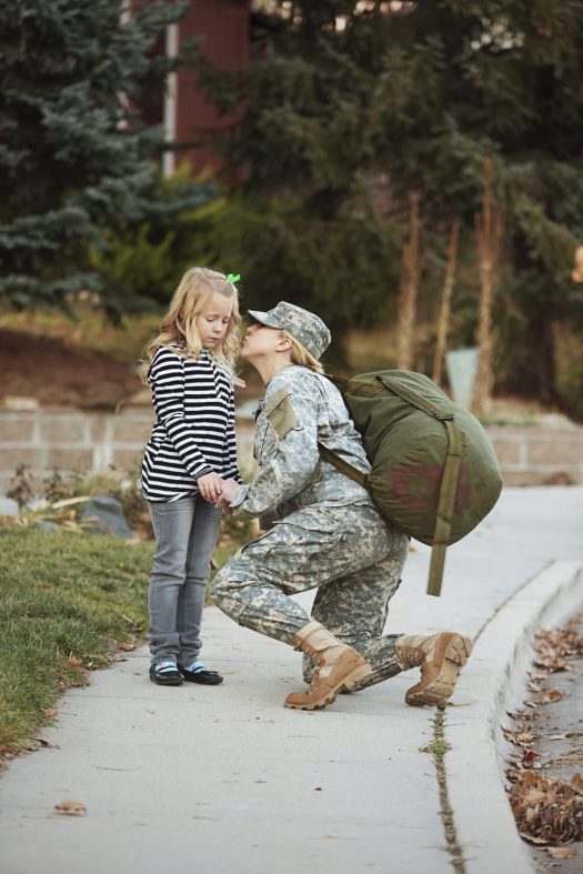 Military mom kissing sad daughter