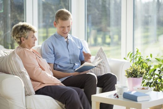 Mother and adult son on couch reading book together