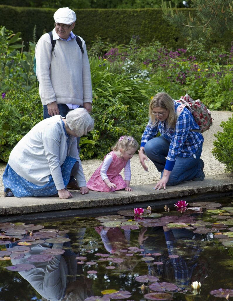 Grandparents with daughter and granddaughter at a pond.