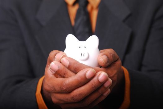 Man's hands holding a small white piggy bank.