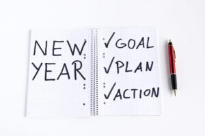 A notepad with New Year written on the left side and Goal, Plan, Action written on the right side
