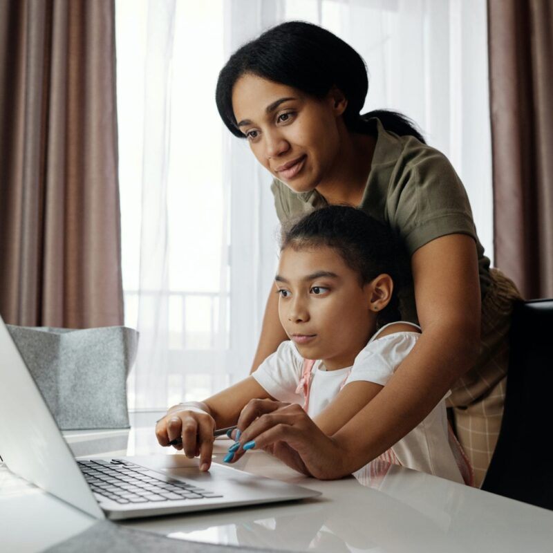 Woman helping child use computer