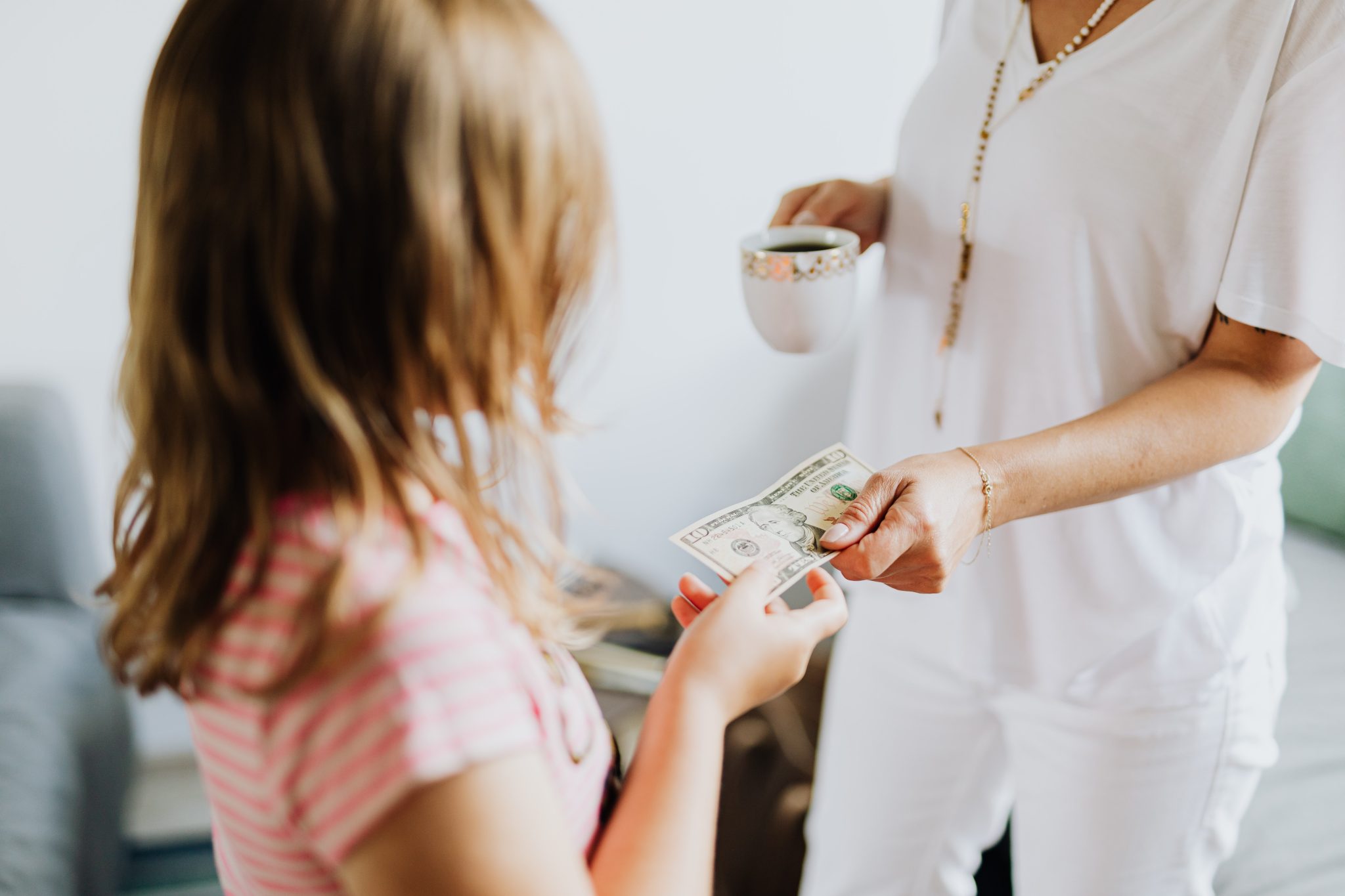 Adult woman handing young child $10 bill