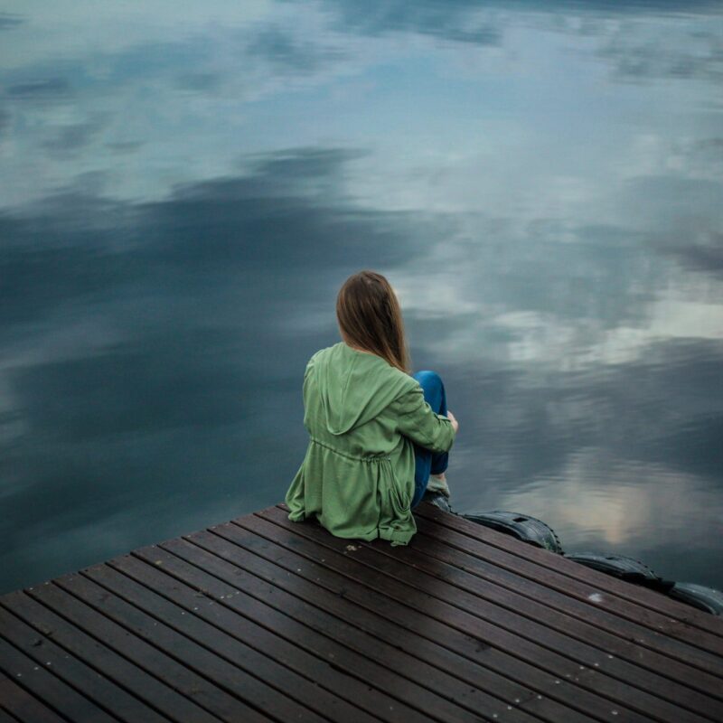 Woman Sitting on Wooden Planks over water