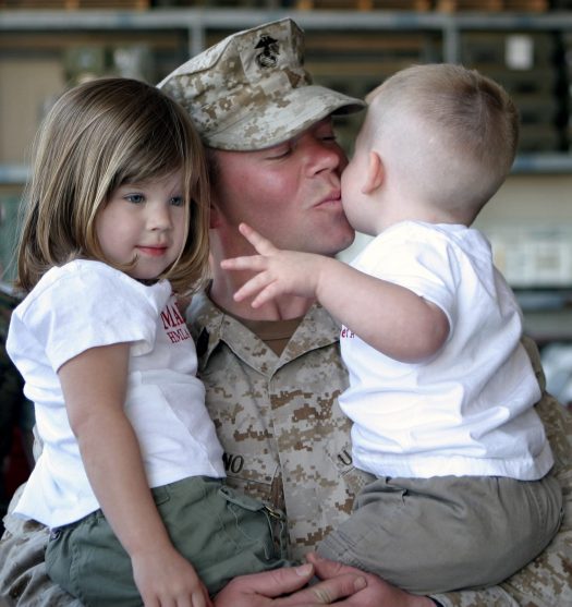 Man holding and kissing two children