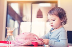 young girl unpacking her backpack at home