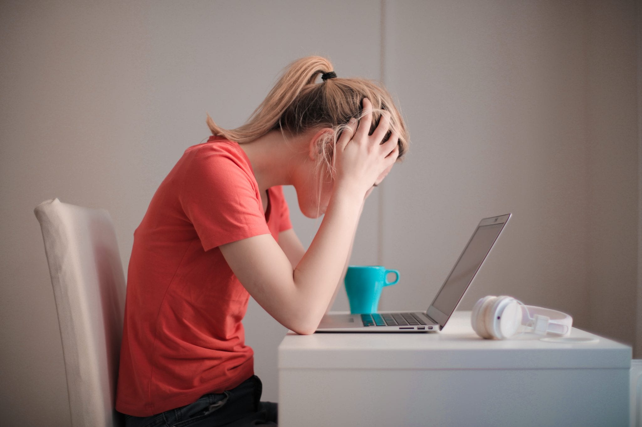 Woman holding her head and sitting in front of laptop