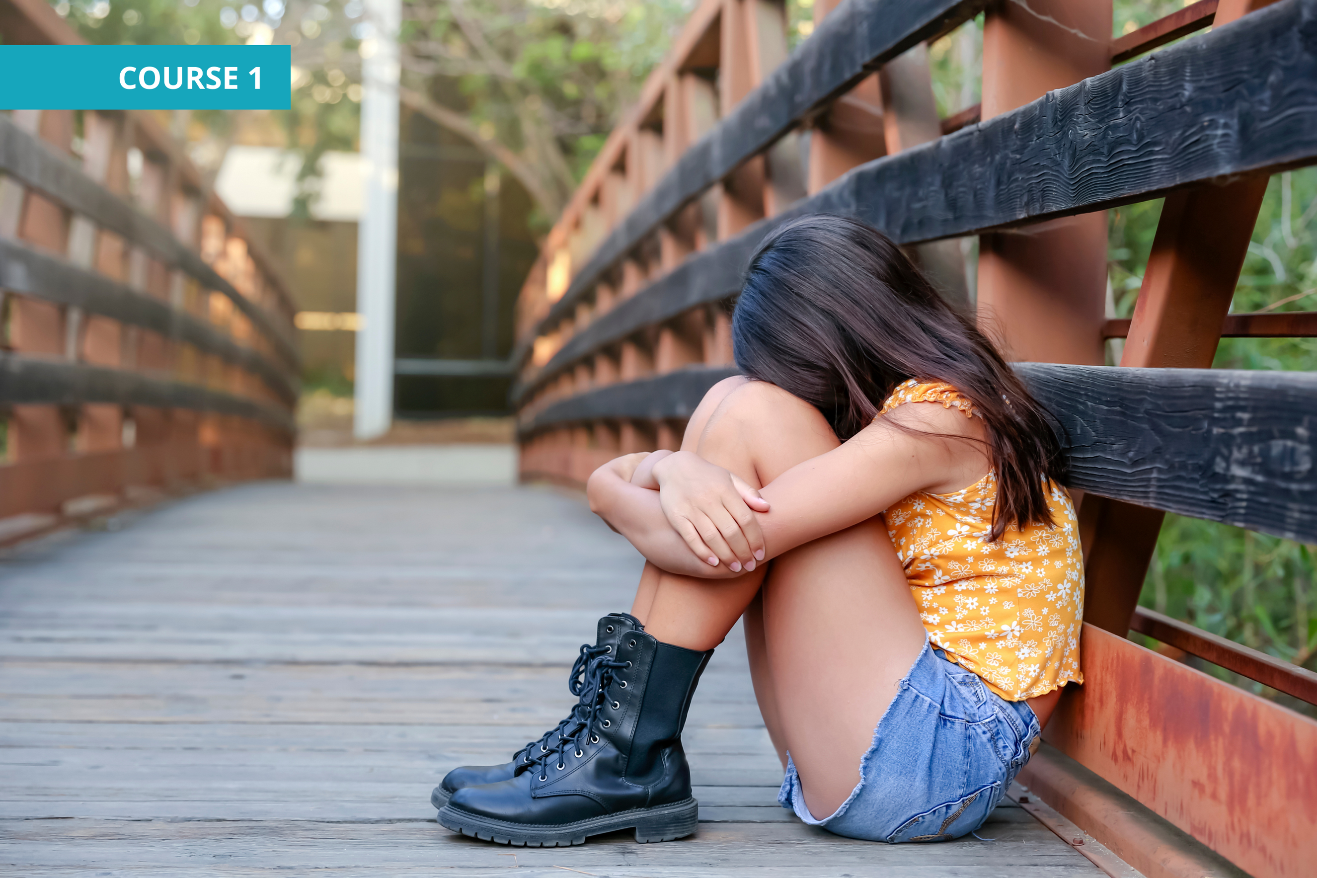 a tween girl sits with her hand on her knees on a bridge