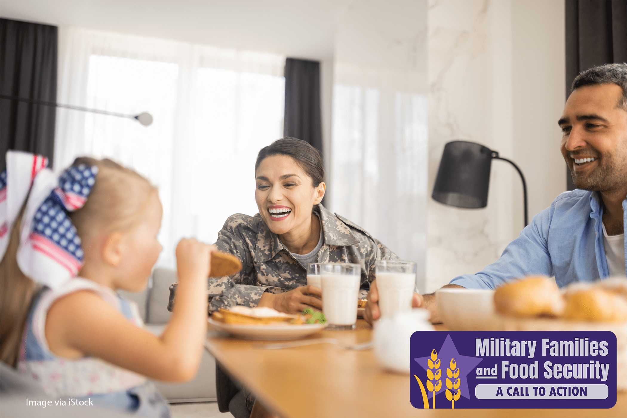 Family sitting at table having a meal, with woman dressed in military fatigues.