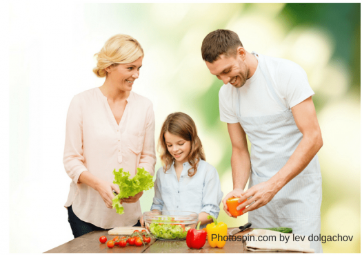 Mother, father, and young daughter preparing salad