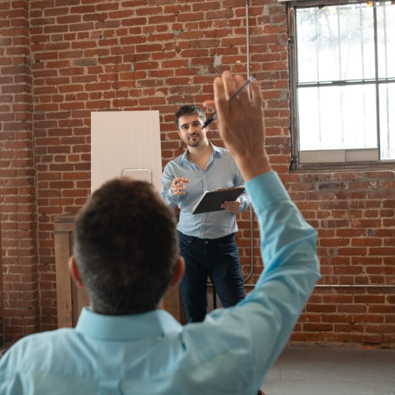 man standing calling on person with hand raised