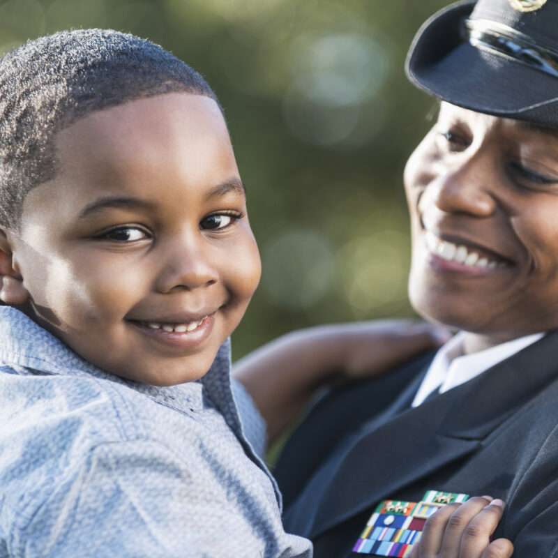 a military officer holds her son in her arms