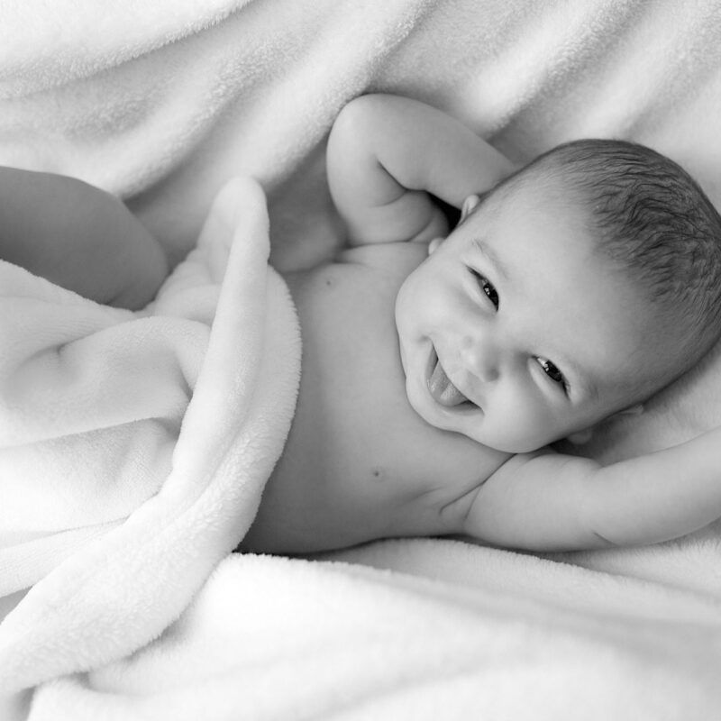 Infant laying wrapped in blankets and smiling