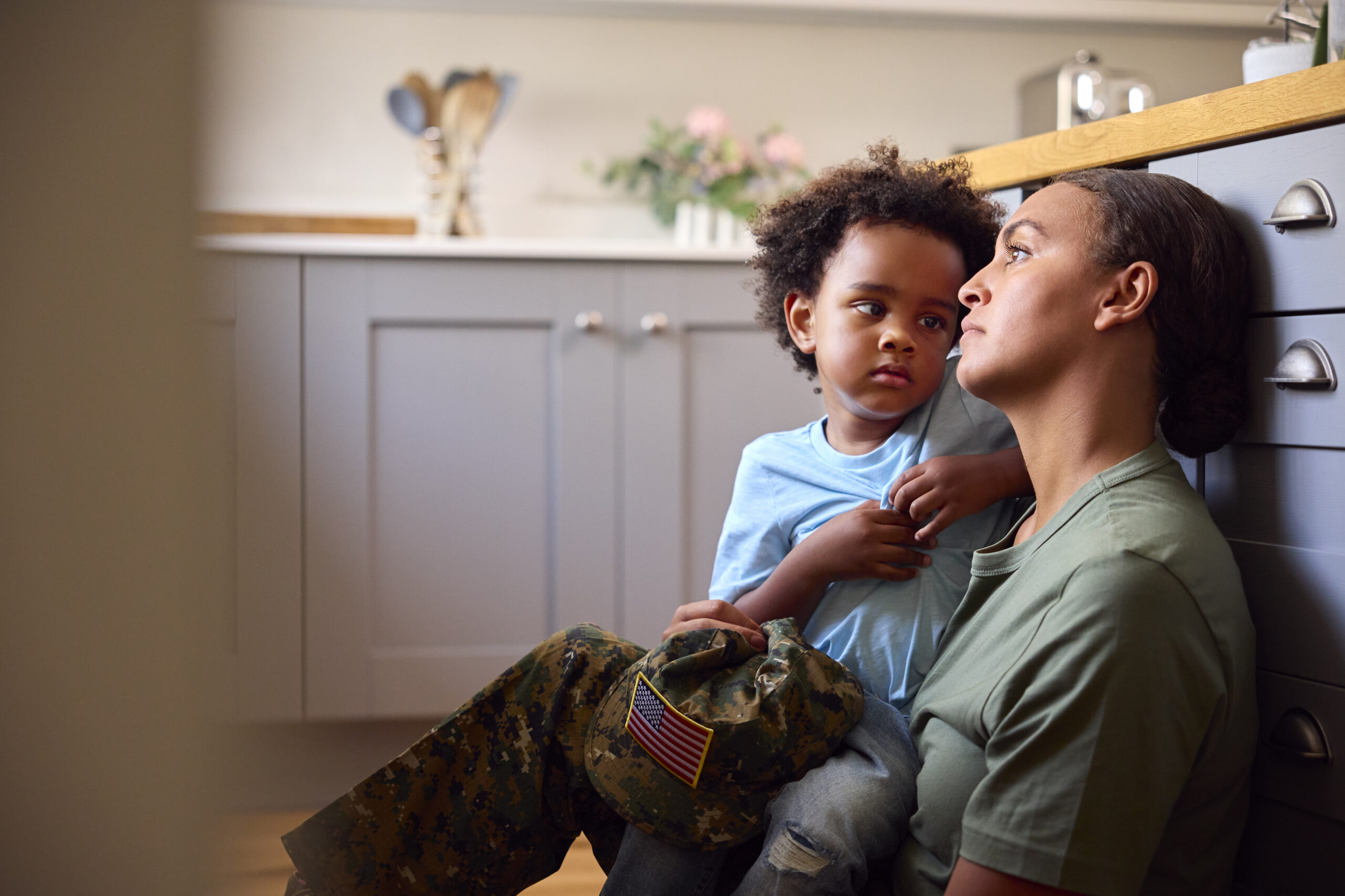 service member parent holds their child, both having looks of concern or stress on their face