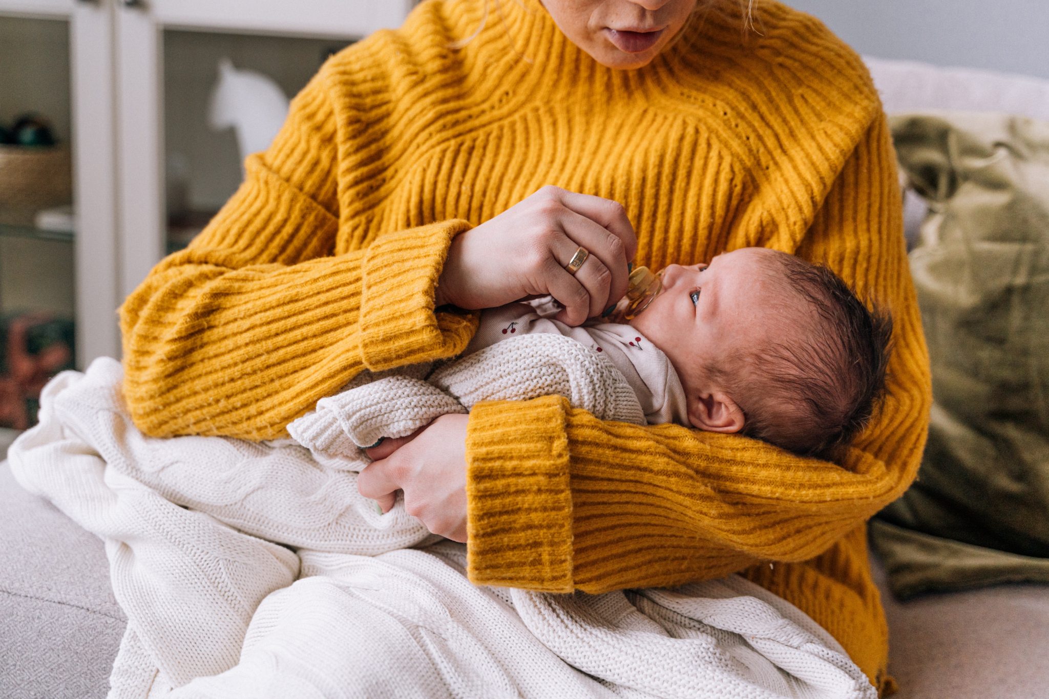Picture of woman in yellow knit sweater holding baby