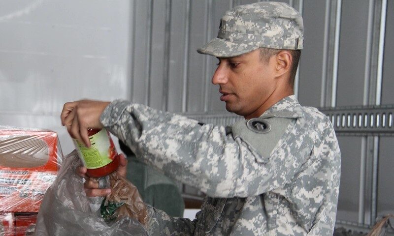 Soldier holding up a can of sauce in a food drive