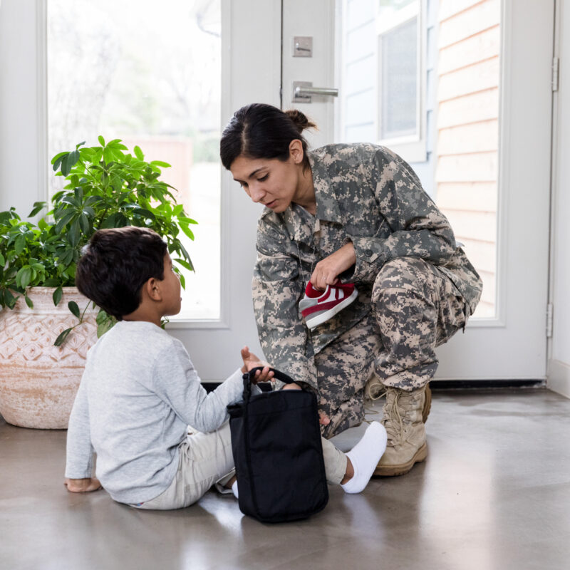 Military mom and son helps him with shoes before school