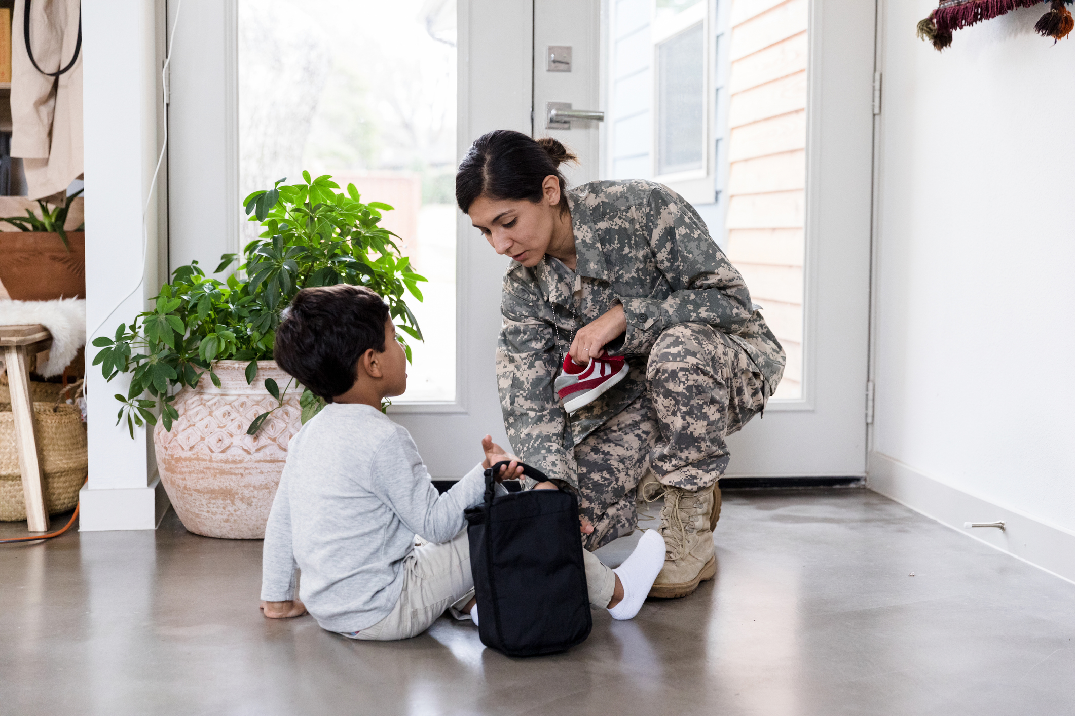 Military mom and son helps him with shoes before school