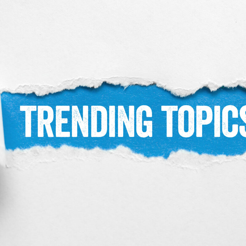 "trending topics" words revealed on a blue background from a torn section of white paper