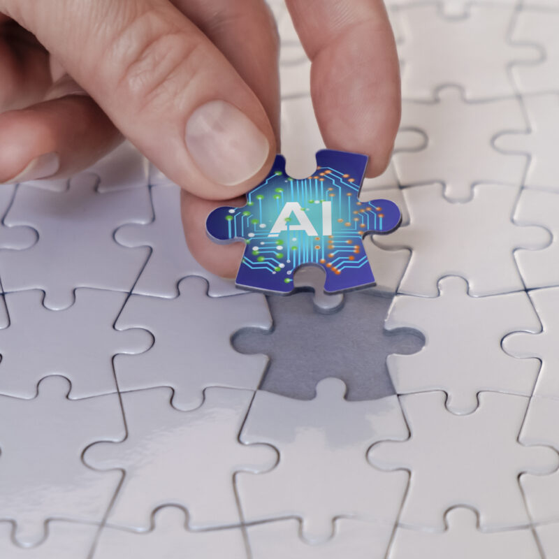 Hand places the last piece of the puzzle, the concept of artificial intelligence.