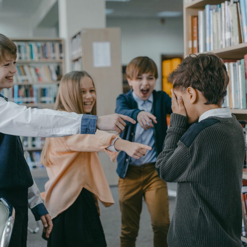 a group of children laughing at a boy in a library