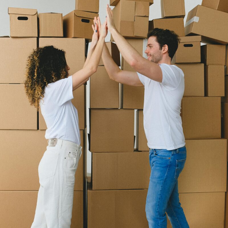 Two people give each other a high five in front of a stack of cardboard boxes