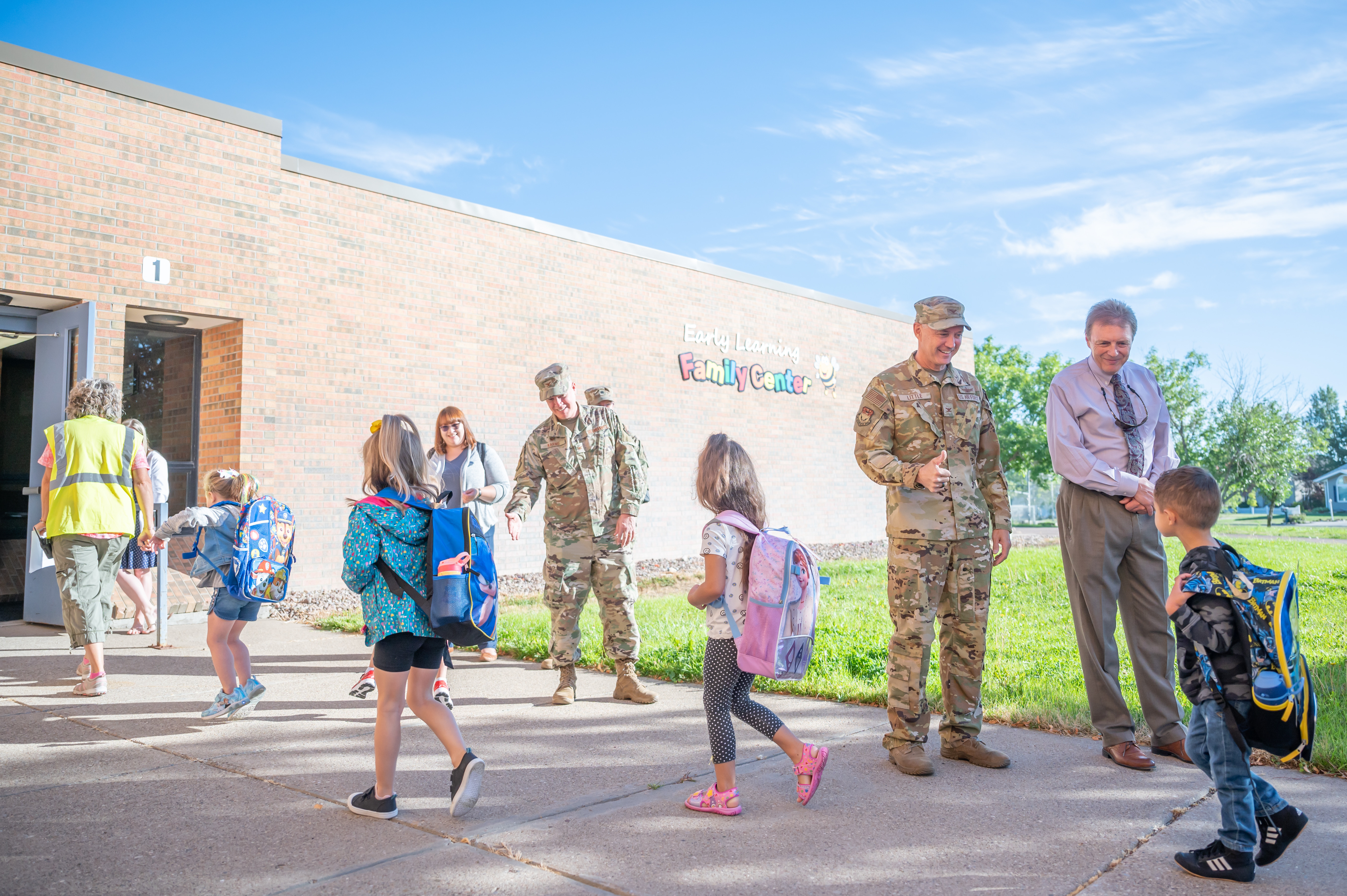 Tom Moore, Great Falls Public Schools superintendent, far right, and Col. Barry Little, 341st Missile Wing commander, right, greet students during the first day of transitional kindergarten at the GFPS Early Learning Family Center Aug. 29, 2022, in Great Falls Mont. Eighteen families from Malmstrom are enrolled in this pilot program.