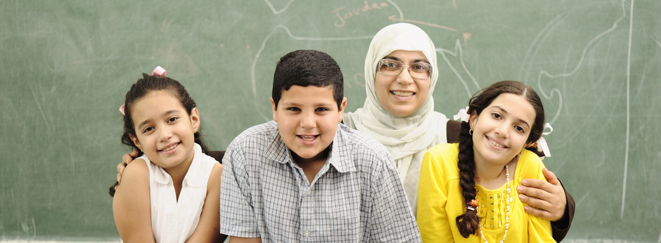 Three students and their teacher in a school classroom