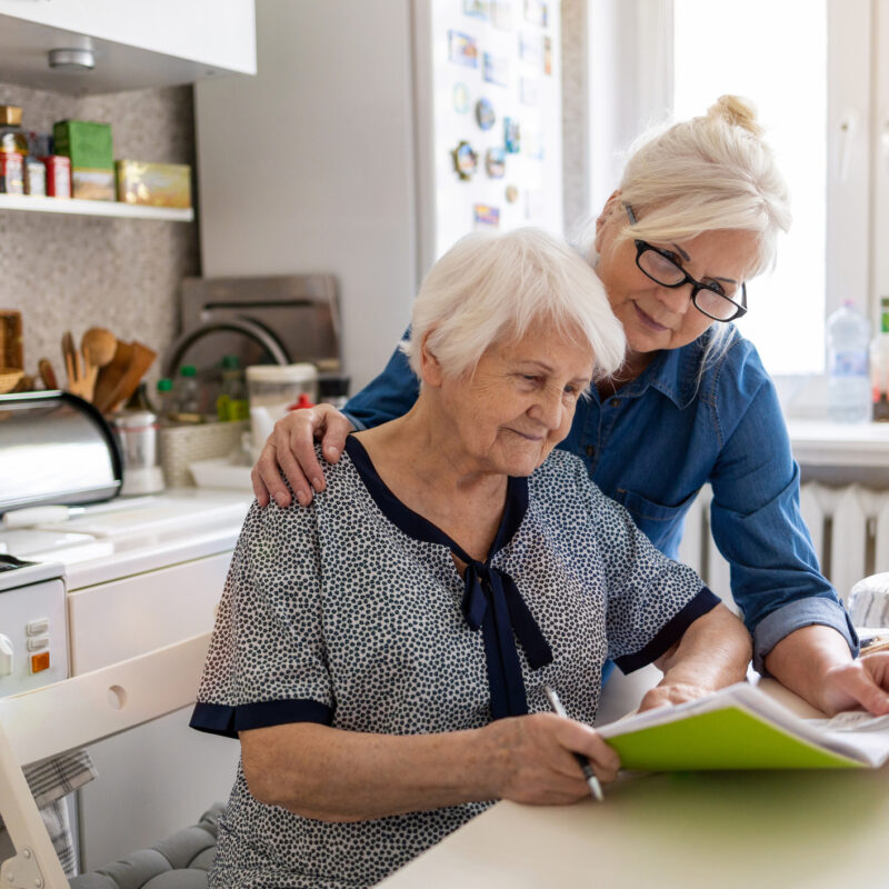 Mature woman helping elderly mother with paperwork