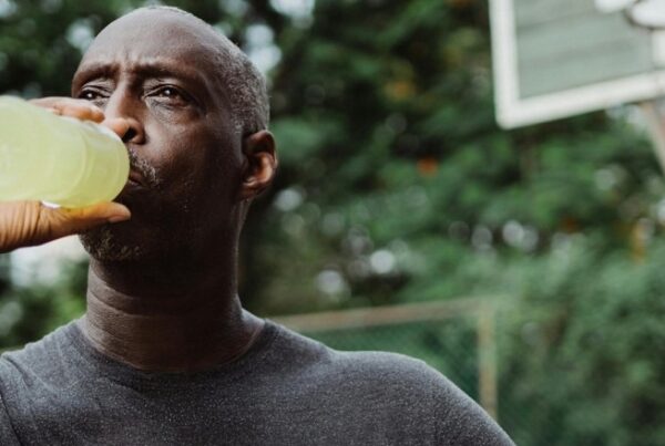 African American male holding a basketball drinking an energy drink or electrolyte replacement