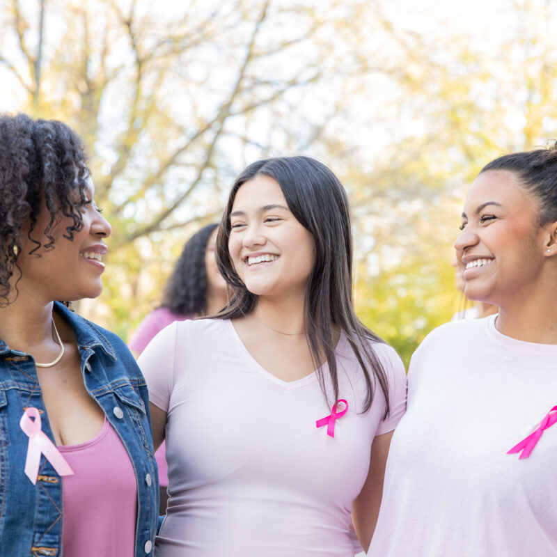 Diverse group of young women smile while attending pink ribbon breast cancer charity event