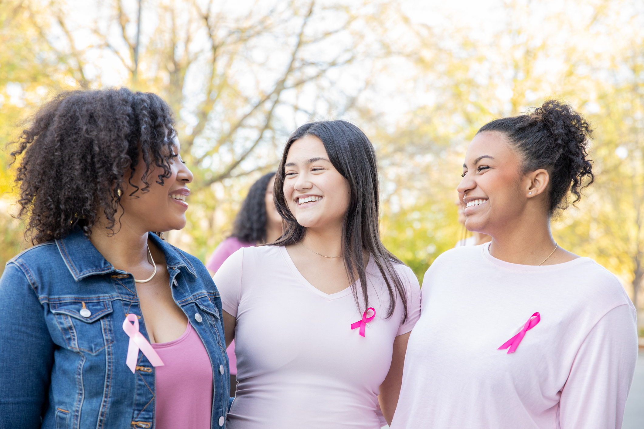 Diverse group of young women smile while attending pink ribbon breast cancer charity event