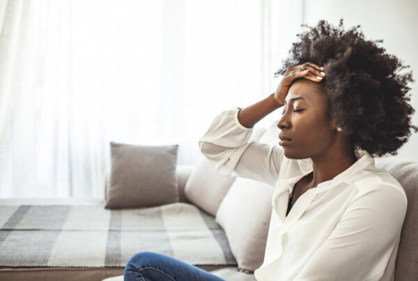 Lonely sad woman deep in thoughts sitting daydreaming or waiting for someone in the living room with a serious expression, she is pensive and suffering from insomnia sitting on couch