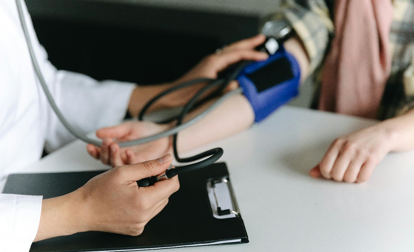 Medical professional obtaining a manual blood pressure reading from a patient.