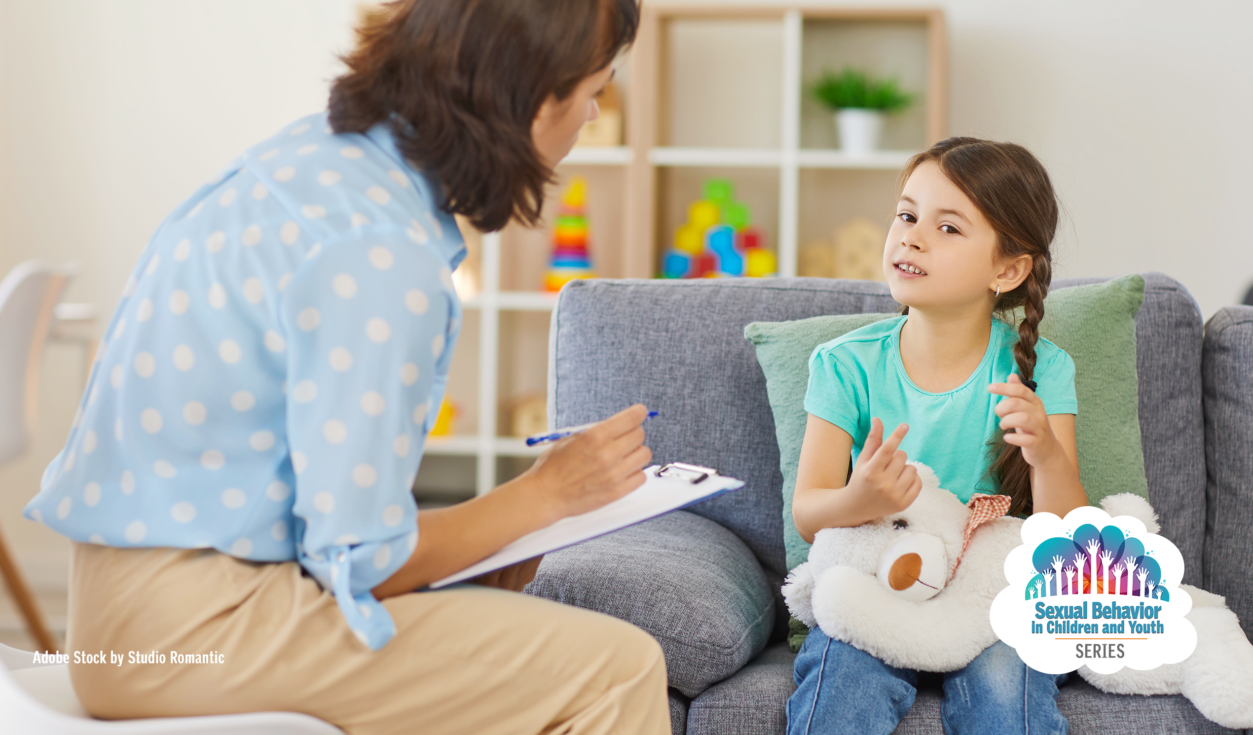 Supportive professional with clipboard listening to girl sharing during a therapy session