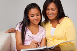 Portrait of a mother helping her daughter with homework.