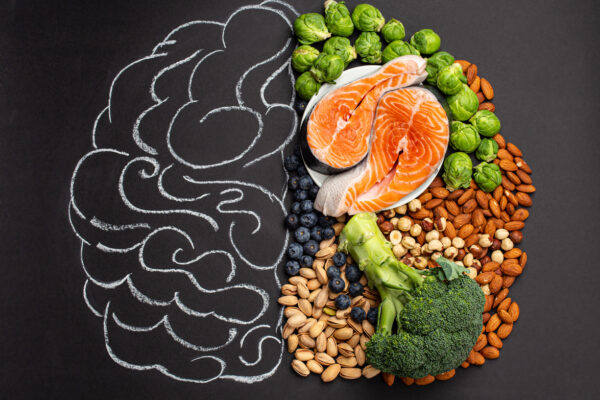 Chalk hand drawn brain with assorted food, food for brain health and good memory: fresh salmon fish, green vegetables, nuts, berries on black background. Foods to boost brain power, top view