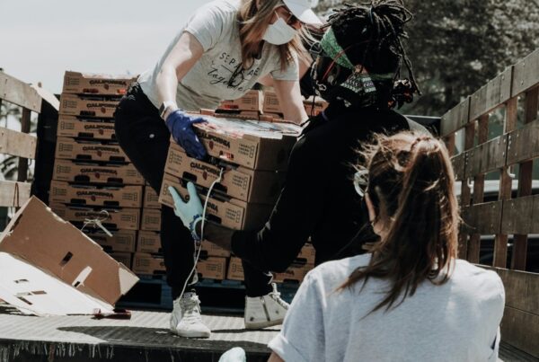 Three females unloading a truck of produce for a mobile food pantry.