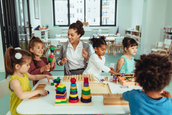Kids and teacher sitting at the table and playing with toys