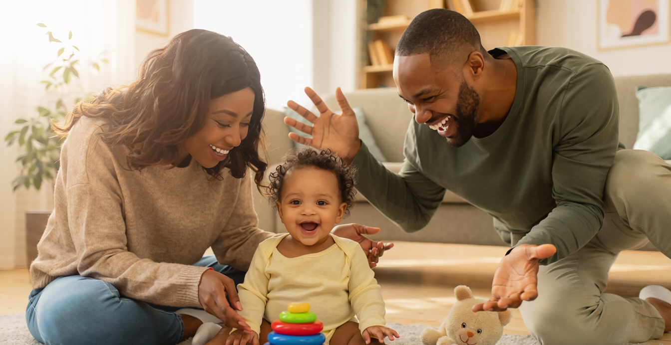 A young couple playing with their infant on the floor