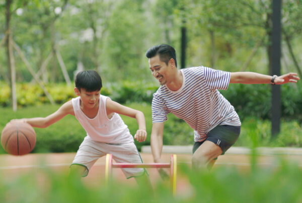 Asian father & son playing basketball in garden in morning