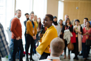 Photo featuring a group of professionals listening to a speaker.