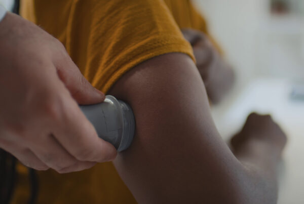 Close up shot of hands of unrecognizable medical practitioner implanting continuous glucose monitor on upper arm.