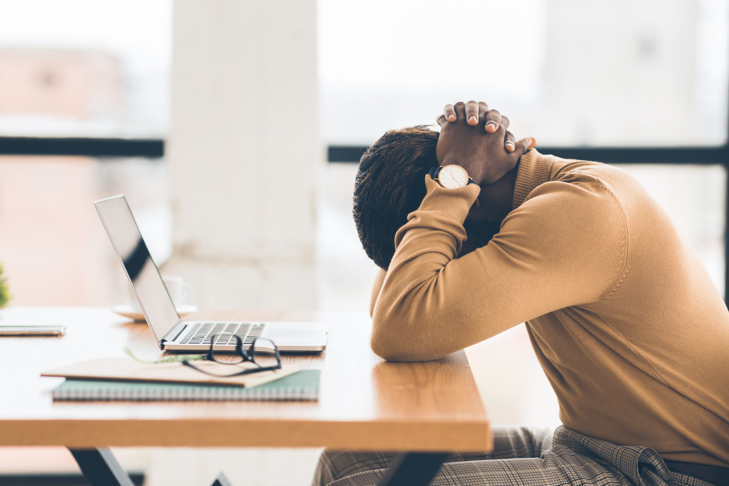 Businessman feeling upset and desperate, working at office, hands on head.