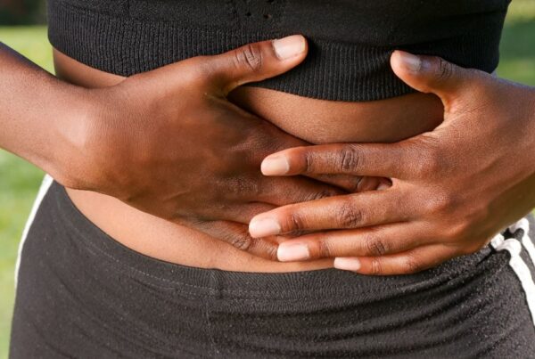 Female with both hands holding abdomen.