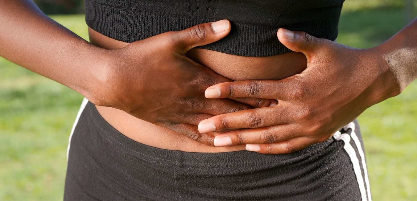 Female with both hands holding abdomen.